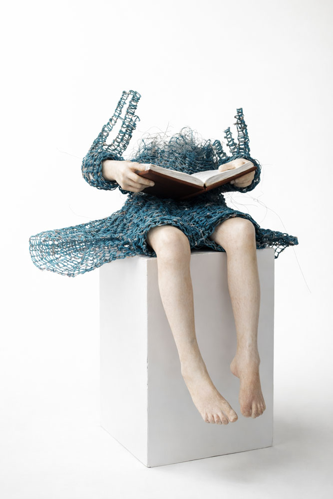 Untitled di Lene Kilde è una scultura in jesmonite, acciaio, rame e legno. La figura di una bambina che legge evoca l’intimità e l’immaginazione dell’infanzia. Esposta alla Galleria PUNTO SULL’ARTE, Varese, Italia